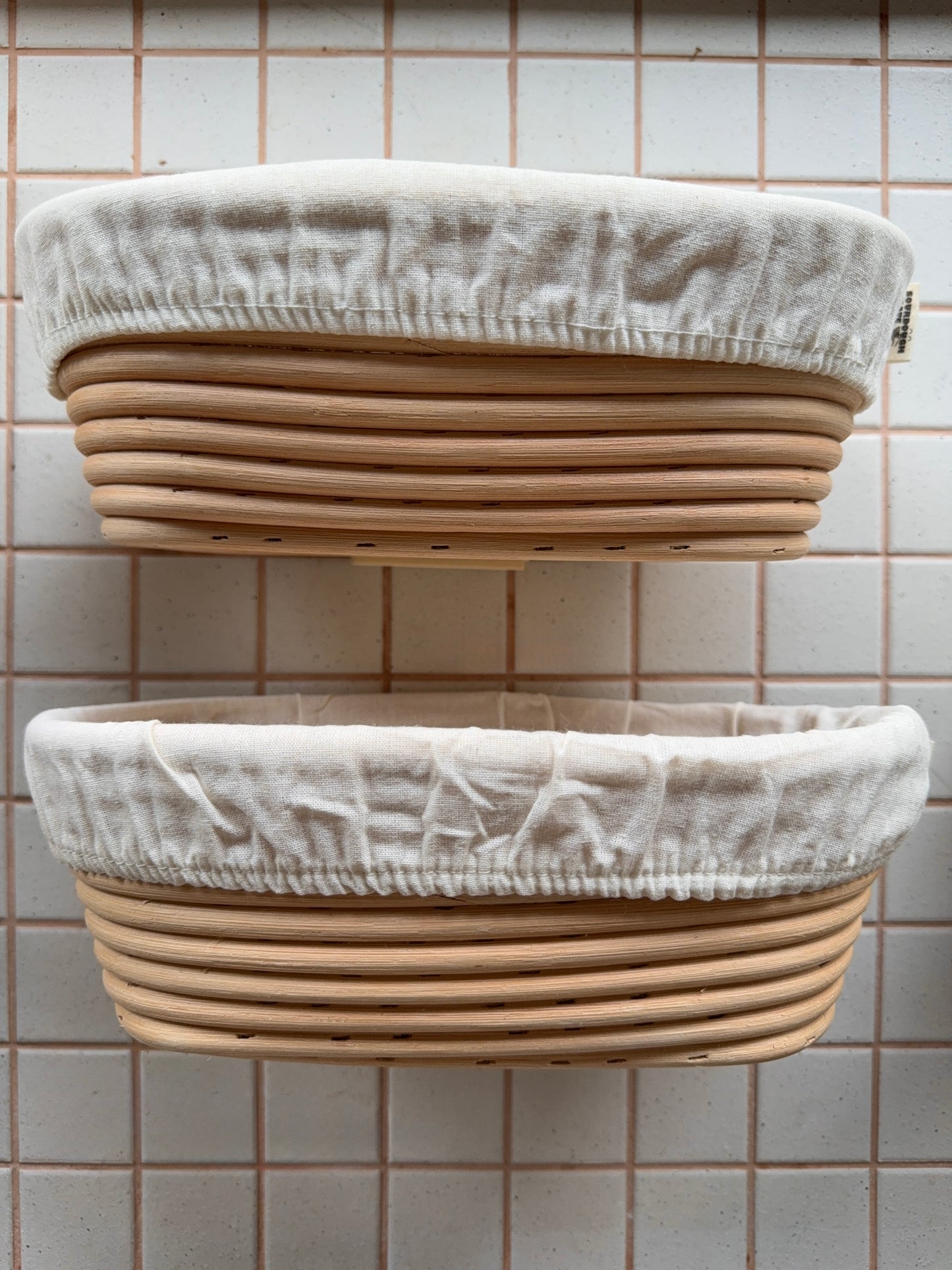 Two woven baskets with fabric covers against a tiled wall.