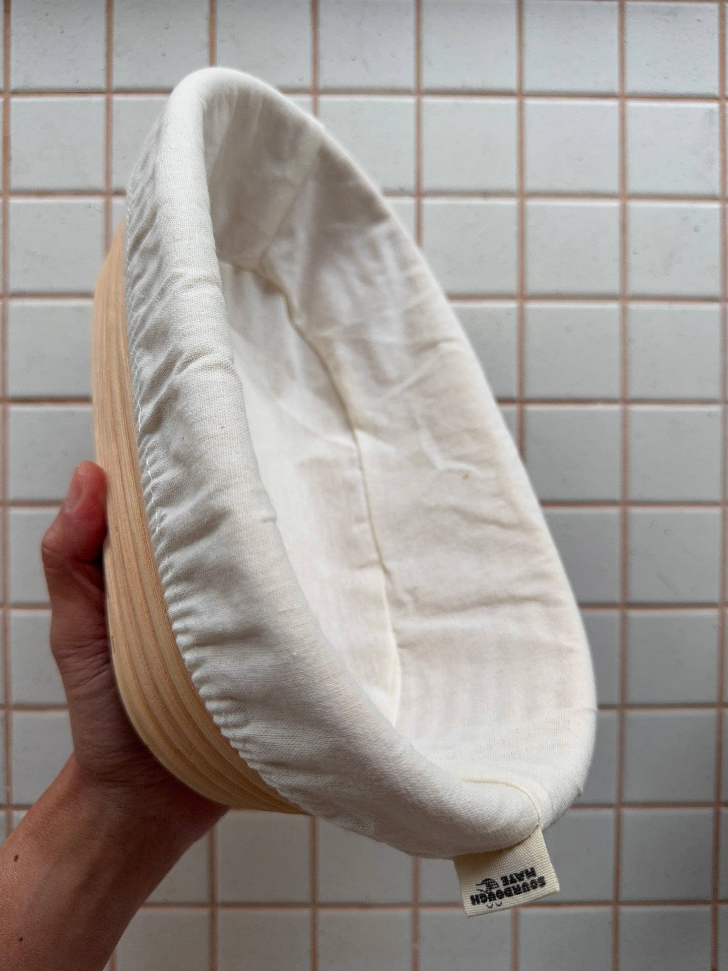 White circular object held by a hand against a tiled wall background